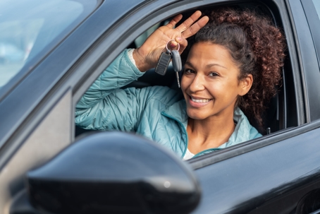 Woman happy in a car holding up keys